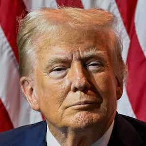 Donald Trump stares forward while seated on stage