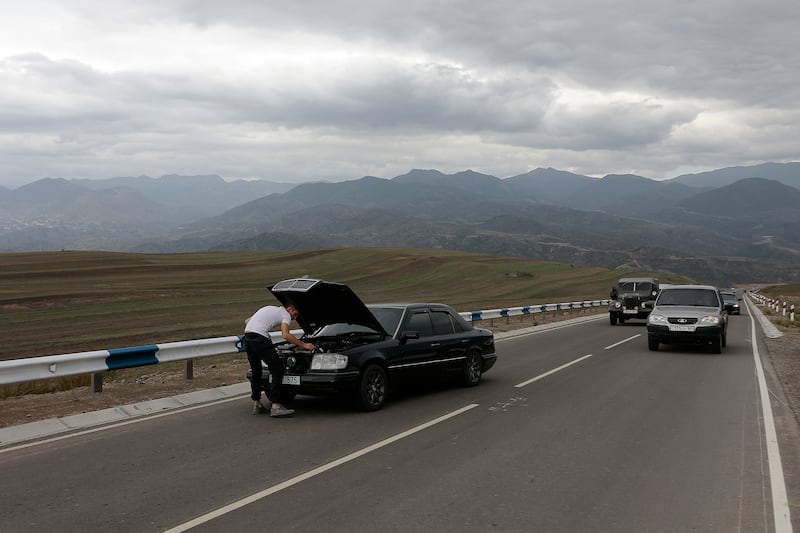 A person works on a broken down car as Armenians flee Nagorno-Karabakh.