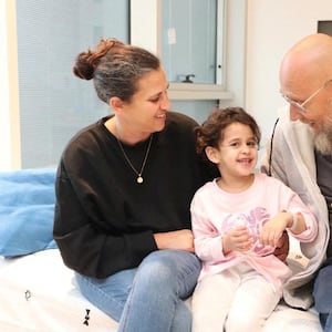 Abigail Edan smiles with loved ones inside a hospital room.