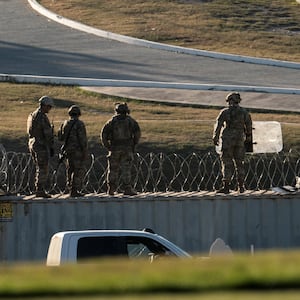 U.S. National Guard soldiers stand on shipping containers which are used as border fences on the bank of the Rio Grande river in Eagle Pass, Texas.