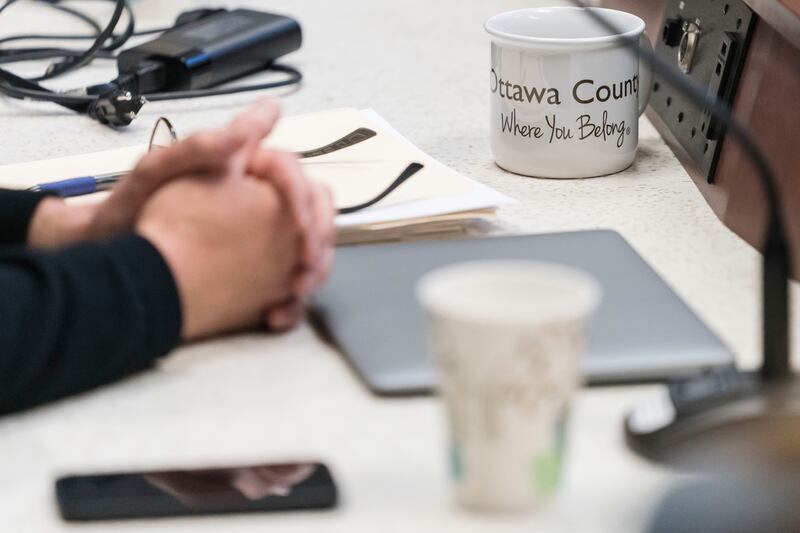 A coffee cup with the tagline "Where You Belong" is pictured in front of Ottawa County Commissioner Doug Zylstra