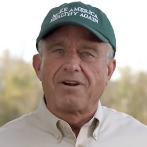 Robert F. Kennedy Jr. stands in a field wearing a Make America Healthy Again hat.