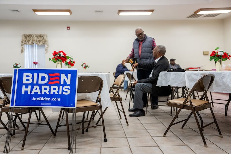  Two black men mill around a room filled with pro Biden posters.