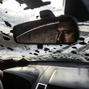 A Ukrainian soldier driving in Kupiansk can be seen in his rearview mirror