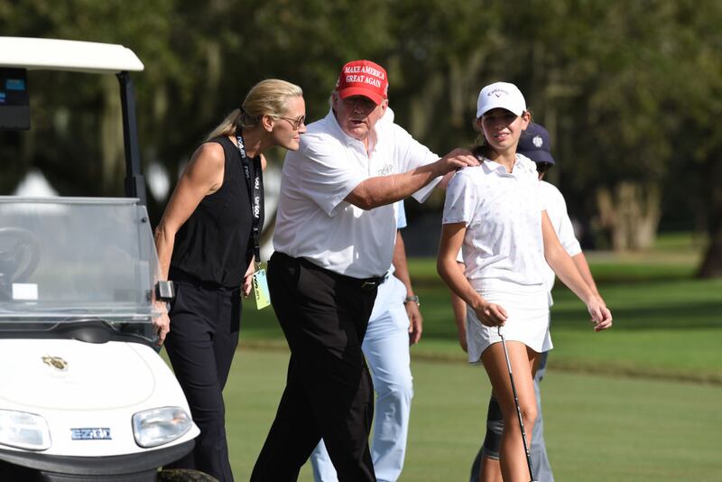 Former President Donald Trump, center walks with his granddaughter Kai Trump and her mom Vanessa Trump during a 2022 golf tournament. 