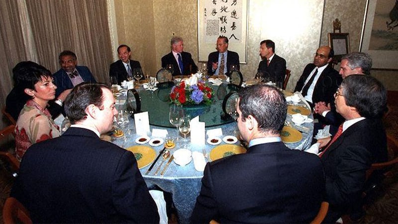 A photograph shows a group of people sitting around a dinner table that includes Goh Chok, Bill Clinton, Ghislaine Maxwell, and Jeffrey Epstein 