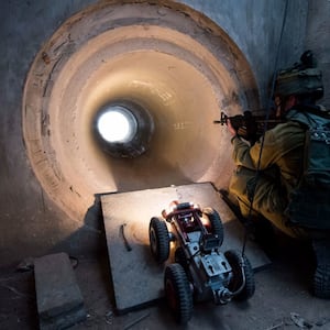 An IDF soldier peers into a tunnel while a drone enters