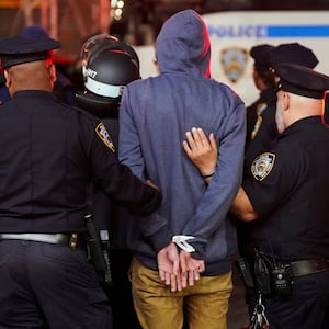 NYPD officers walk a detainee in handcuffs from a Columbia University protest.