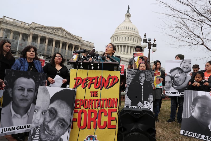 AOC speaking in front of a crowd and behind a lectern marked "Defund the immigration force"