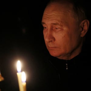 Russian President Vladimir Putin lights a candle in up close picture.