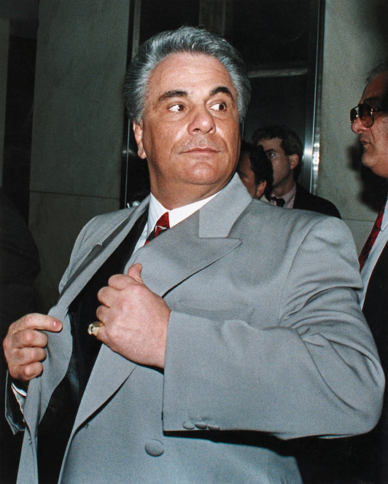 John Gotti, the Dapper Don, wearing a gray overcoat and dark suit, white shirt and red tie