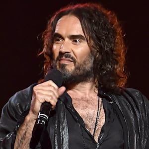 Russell Brand speaks into a microphone at the MusiCares Person of the Year ceremony.