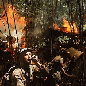 U.S. Army Special Forces Capt. Vernon Gillespie contacting his base camp by radio while Vietnamese soldiers burn down a National Liberation Front hideout.