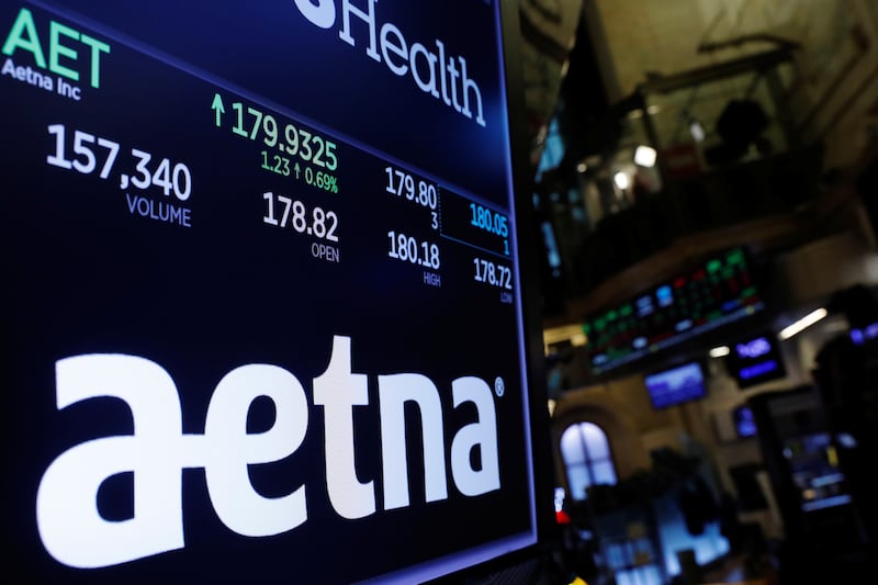 A logo of Aetna is displayed on a monitor above the floor of the New York Stock Exchange.