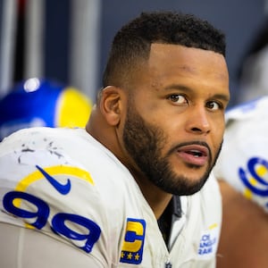 Aaron Donald stares to his right as he sits on the bench in uniform during an NFL game.