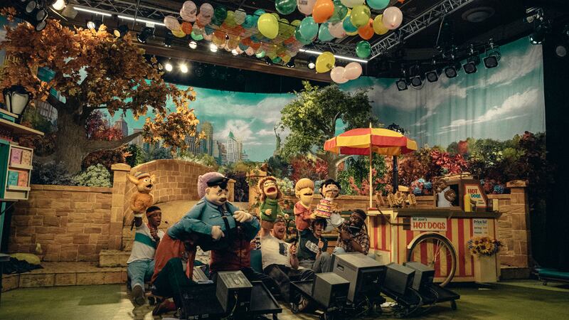 Puppeteers hold up puppets on the set of a kids show in a still from 'Eric'