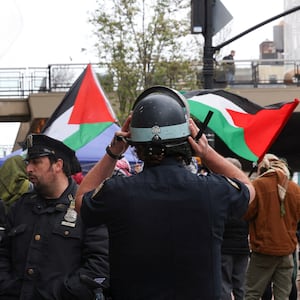 NYPD officers stand in front of protesters waving Palestinian flags.