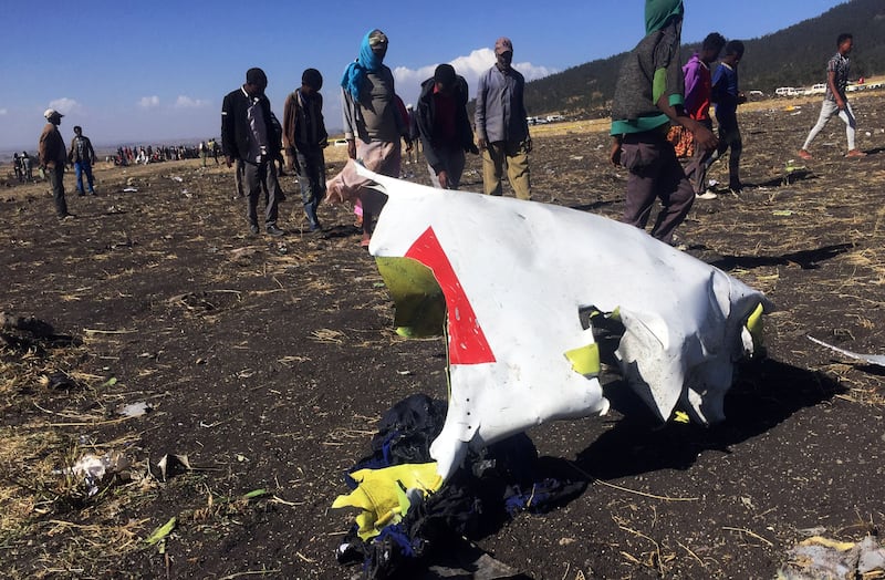 People walk past a part of the wreckage at the scene of the Ethiopian Airlines Flight ET 302 plane crash