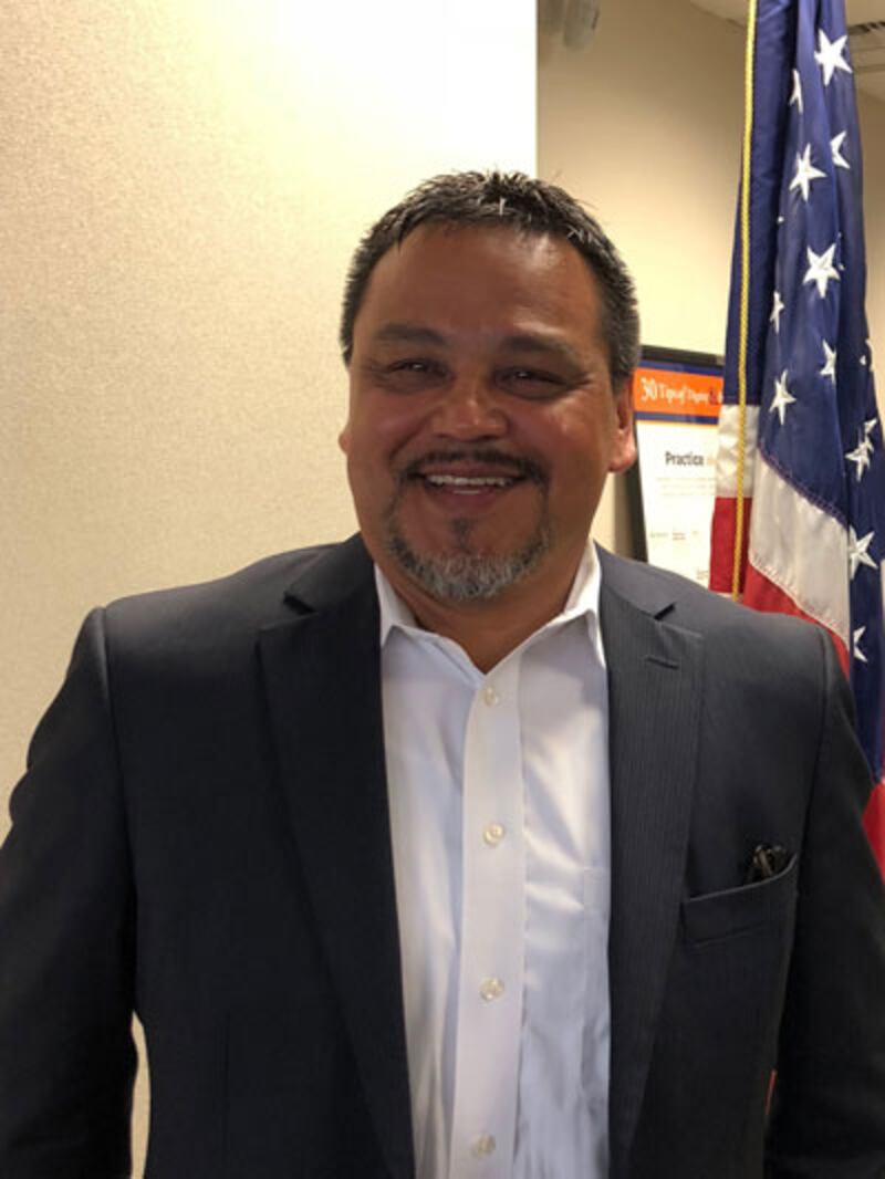 Eugene Peltola Jr. smiling in a suit.