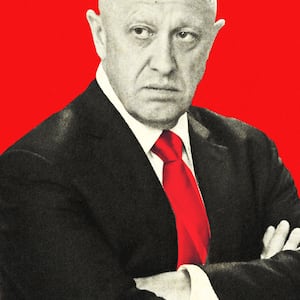 Yevgeny Prigozhin is shown in black and white with his arms crossed and wearing a red tie on a red background