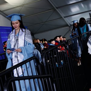 Students from the Columbia School of Professional Studies wear keffiyehs and celebrate after walking the stage during the schools graduation ceremony.