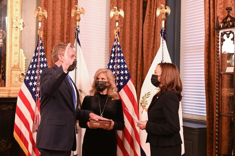 Jeff Flake and Kamala Harris stare at each other while wearing masks at a swearing in ceremony.