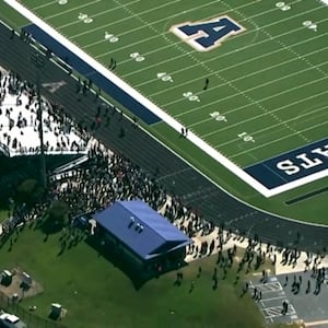 Students and staff gather next to the football field after law enforcement officers responded to a fatal shooting at Apalachee High School.