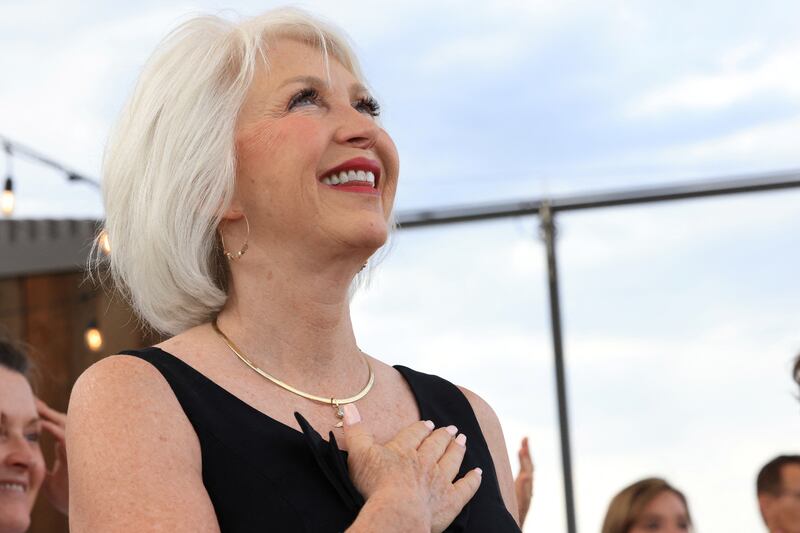 Tina Peters smiles outside with her hand over her heart.