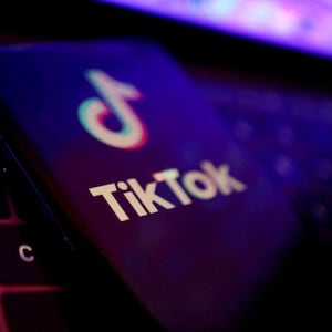 An illustration of the TikTok logo on a phone atop a laptop keyboard