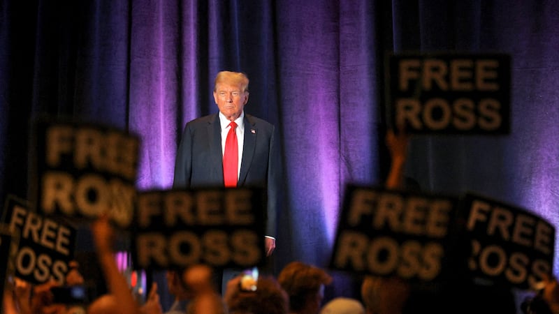 Supporters of jailed Silk Road founder Ross Ulbricht hold placards as Donald Trump addresses Libertarian Party convention in D.C.