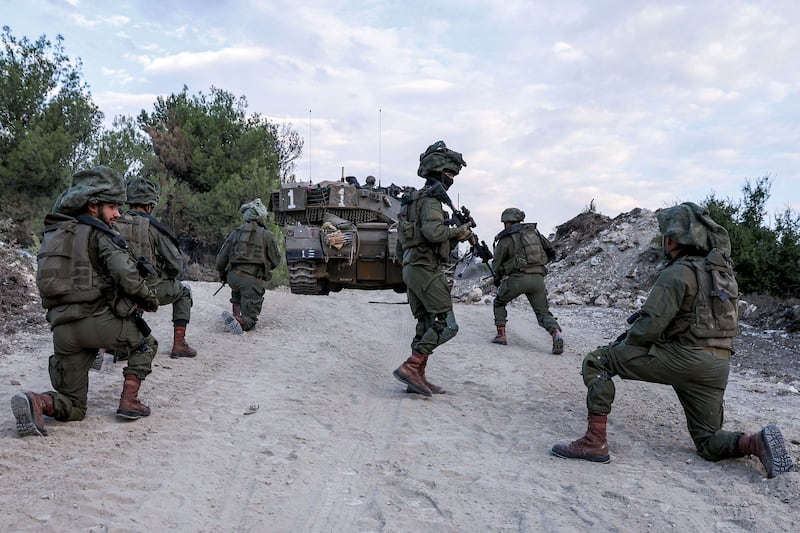 Israeli soldiers wait on a dirt road