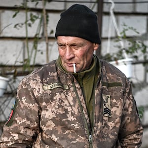 A Ukrainian soldier smoking a cigarette as the others try to fix the dune buggy.