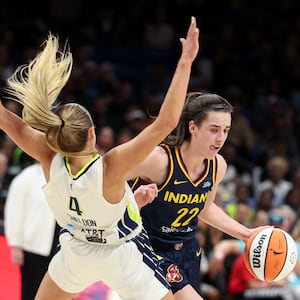 Caitlin Clark #22 of the Indiana Fever drives to the basket against Jacy Sheldon #4 of the Dallas Wings