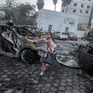 A girl tries to collect usable belongings amid wreckage of vehicles after Al-Ahli Baptist Hospital was hit in Gaza City, Gaza on Oct. 18, 2023.