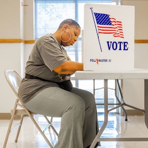 A woman seated at a polling station votes