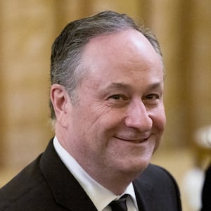 Doug Emhoff smiles while walking near his wife