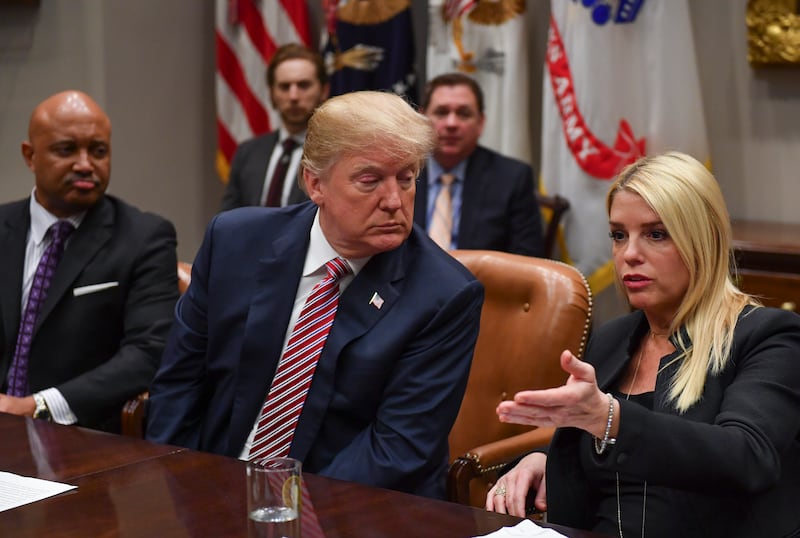 President Donald Trump listens while seated next to Indiana Attorney General Curtis Hill, left, as Florida Attorney General Pam Bondi, right, speaks during a meeting with state and local officials on school safety in the Roosevelt Room at The White House on February 22, 2018 in Washington, D.C.