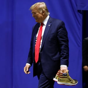 Former President Donald Trump holding a pair of gold Trump-branded shoes