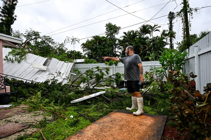 Dan Jones points toward a destroyed roof in his backyard after a tornado hit in Fort Myers, Florida, ahead of Hurricane Milton’s landfall.