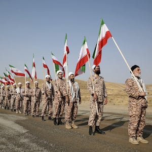 Members of the Islamic Revolutionary Guard Corps (IRGC) stand in a row carrying flags at a military drill