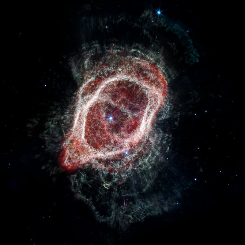 image: The Southern Ring Nebula with stars visible as bright red and blue objects.