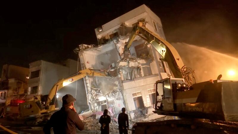 Workers search for survivors in a partially-collapsed building.