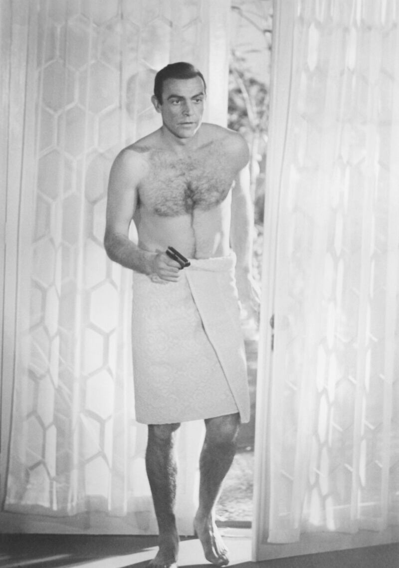 Sean Connery holds gun bare-chested with a towel around his waist as James Bond in the 1963 film From Russia With Love