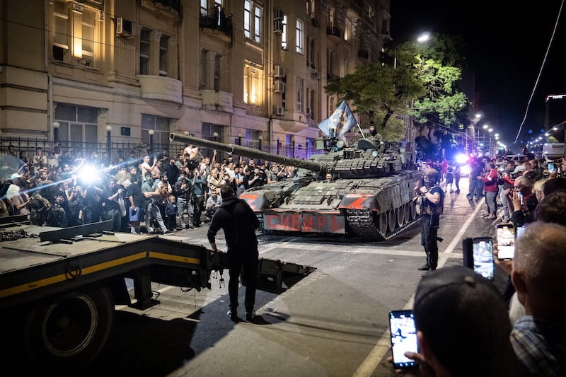 Wagner fighters and military vehichles marching down a street with crowds on the sidelines.