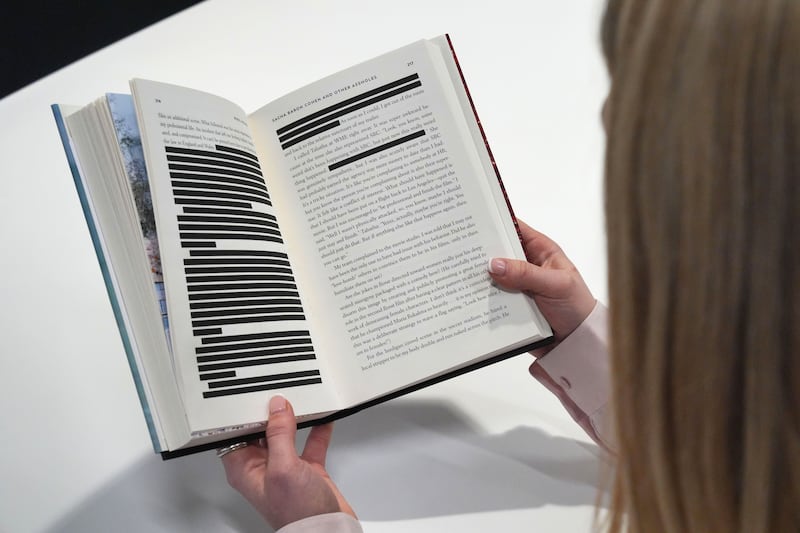 A woman reading a copy of Rebel Rising by Rebel Wilson, the headline-making memoir has been published in the UK with allegations about the actor Sacha Baron Cohen redacted for legal reasons.