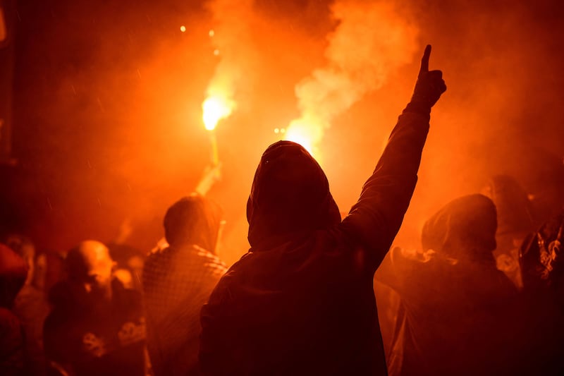 A photo of back of a protestor in the light of a flare during a demonstration in Istanbul