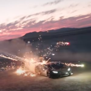 A screenshot from a video showing a Lamborghini Huracan being shot at with fireworks from a helicopter.