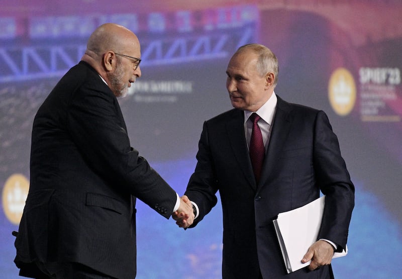 Russian President Vladimir Putin shakes hands with moderator Dimitri Simes.