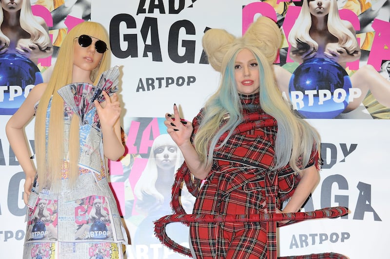 A picture of Lady Gaga posing witha. lifesize Gaga doll