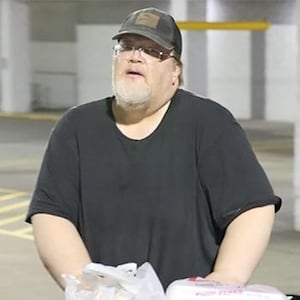 Matthew Brian Cooks walks out of a grocery store with a cart full of groceries.